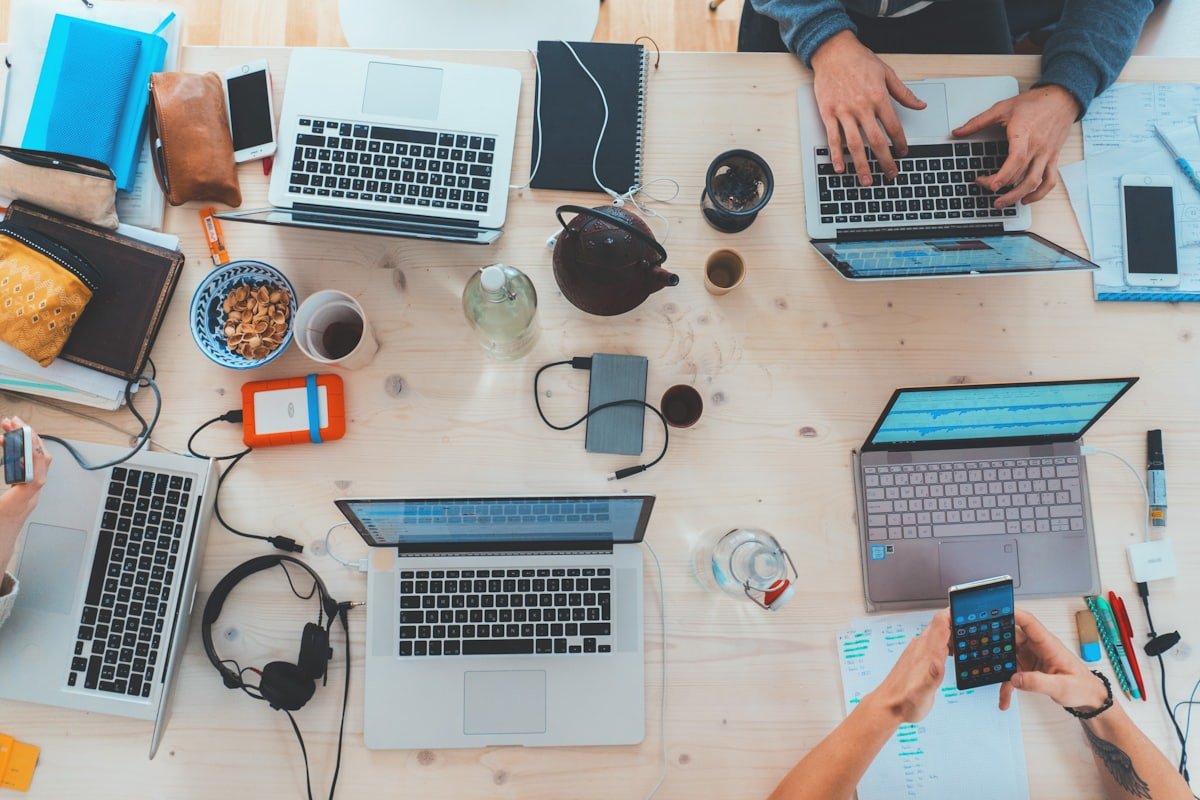 Overhead view of a development team working on laptops, phones and notes around a shared desk